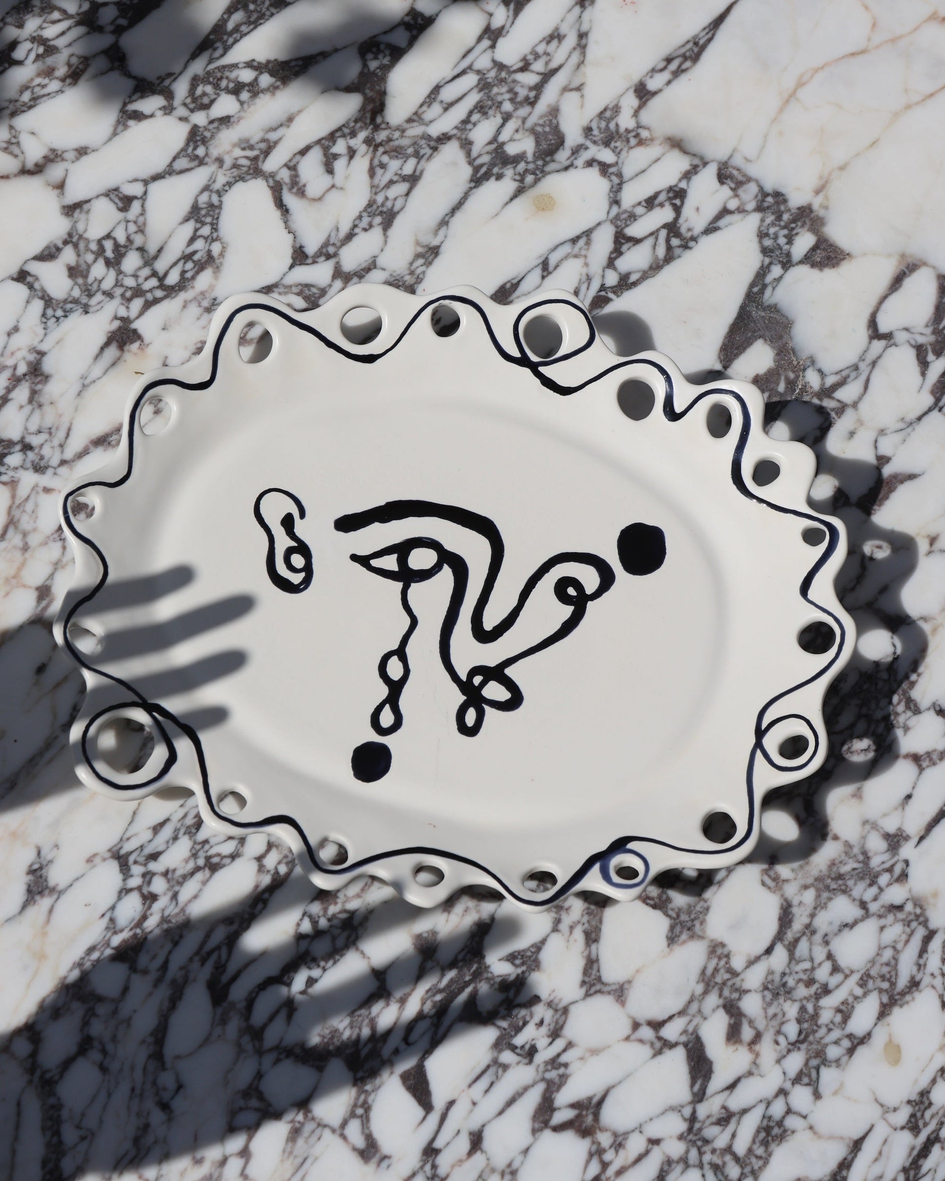 Detail of Wish Platter showing painted face and linework on glazed ceramic surface