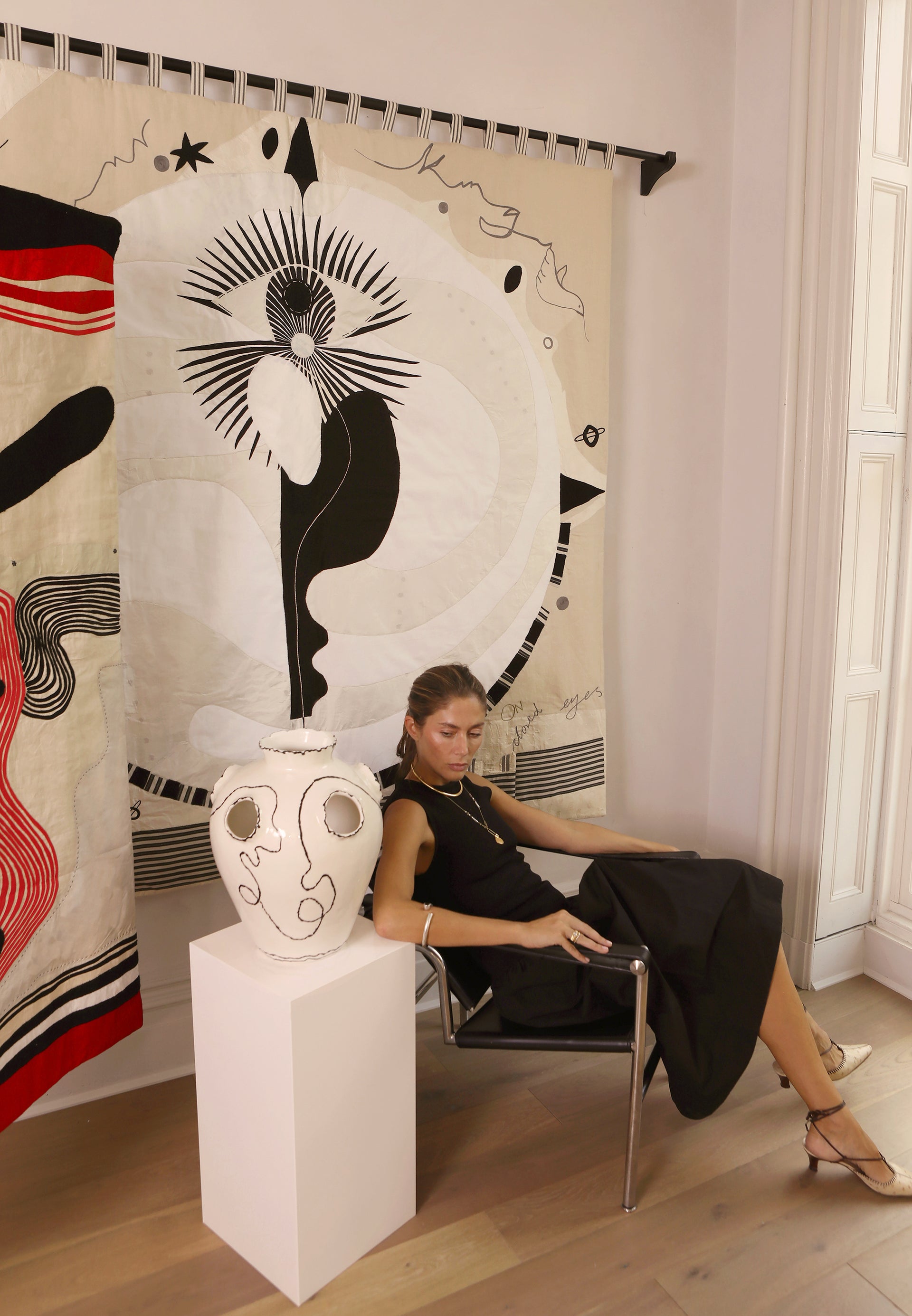 Hand made large decorative tapestry with an abstract and surrealist design motif. A moon design with radiating stars and celestial patterns and line work in an ivory and cream palette. Hand crafted and hand embroidered from antique silks. Made in India, artisanal home decor. Modern tapestry design. Shown in a home setting with modernist home decor and furniture.