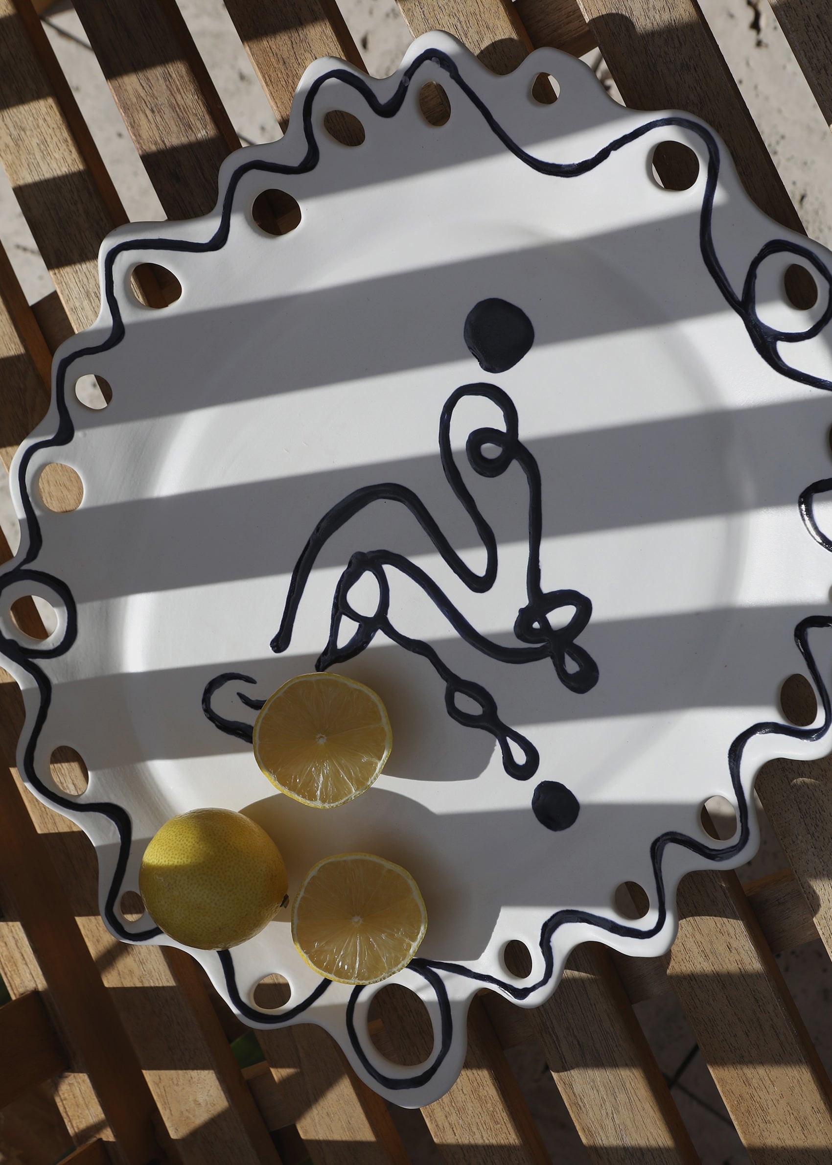 Detail of Wish Platter showing painted face and linework on glazed ceramic surface
