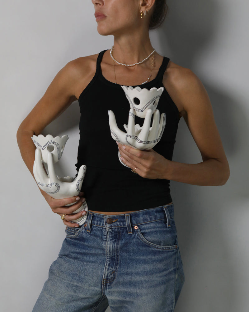 Wish wall mounted hand wall sculpture, held by a woman to show scale. Hand made ceramic sculpture in the shape of a hand with surrealist painted details. 