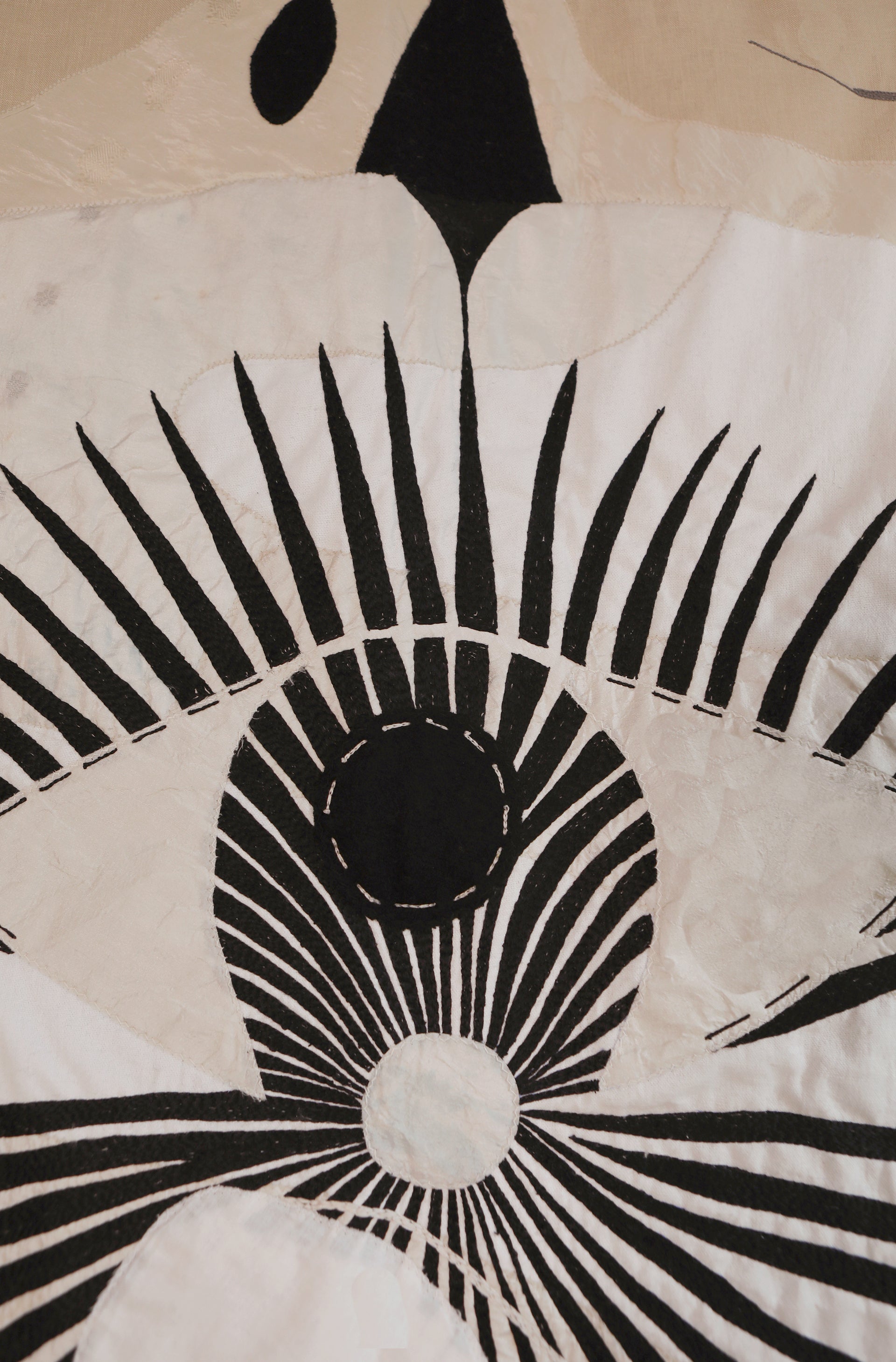 Detail of hand made large decorative tapestry with an abstract and surrealist design motif. A moon design with radiating stars and celestial patterns and line work in an ivory and cream palette. Hand crafted and hand embroidered from antique silks. Made in India, artisanal home decor. Modern tapestry design. 